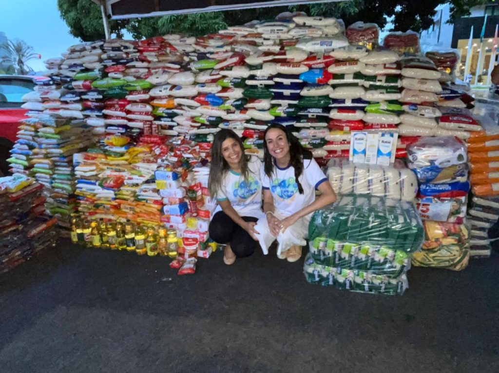 duas mulheres mostrando alimentos que foram doados em uma campanha de doação de alimentos